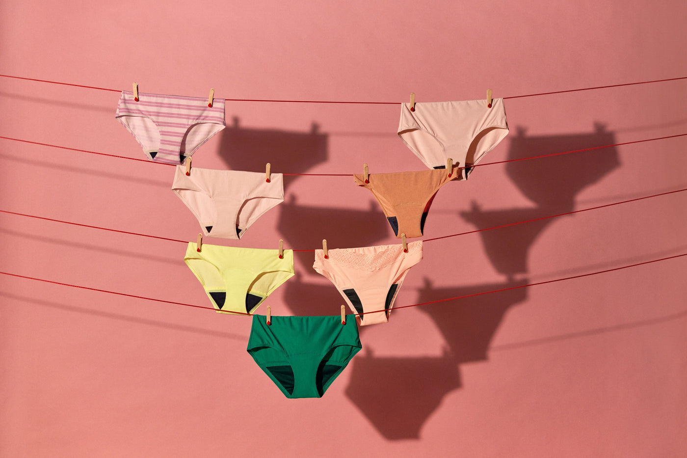 Pairs of period pants of different colours and styles hung to dry on a clothesline.