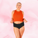 ComfortFit High Waist Light period pants, featuring a high waist design for comfort and protection, shown on a woman wearing an orange top and black bottoms.
